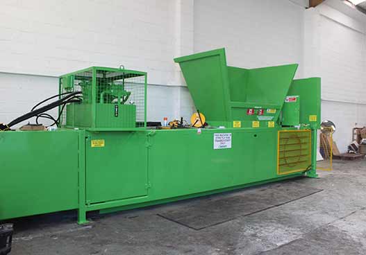 large green compactor next to a pile of cardboard boxes